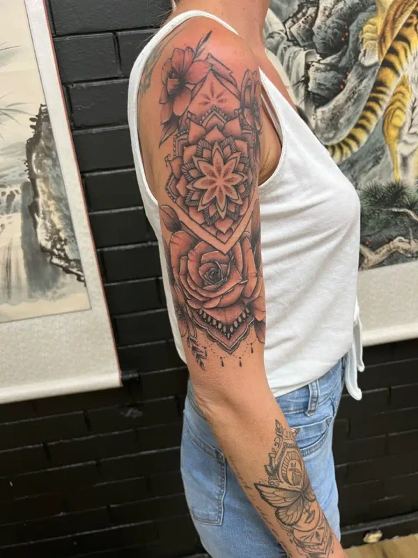 Detailed geometric and floral upper-arm tattoo